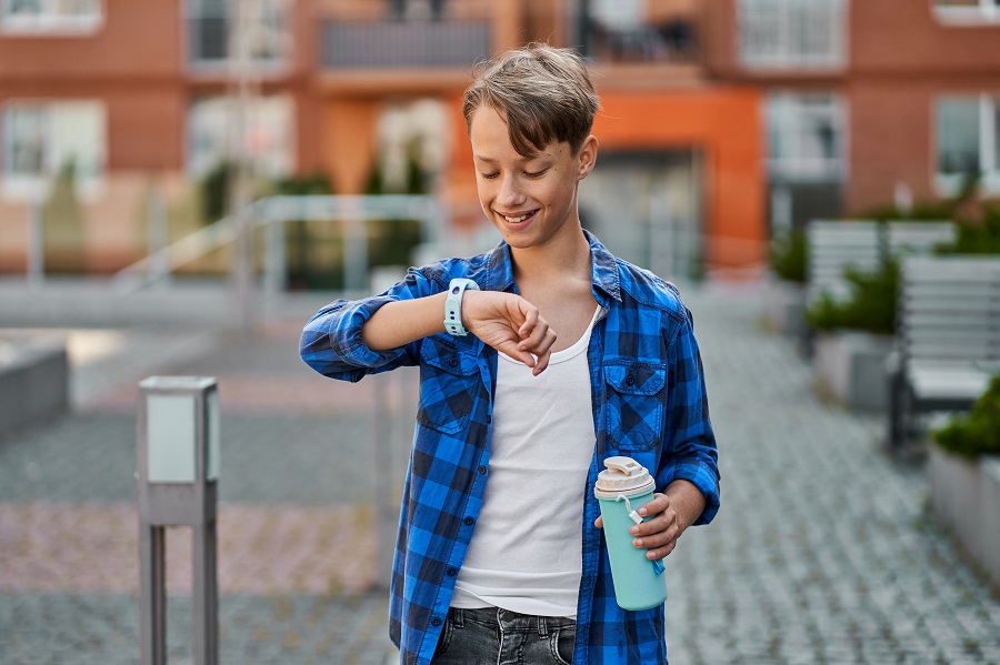 ragazzino-con smartwatch-blu-e-beve-il-te-vicino-alla-scuola
